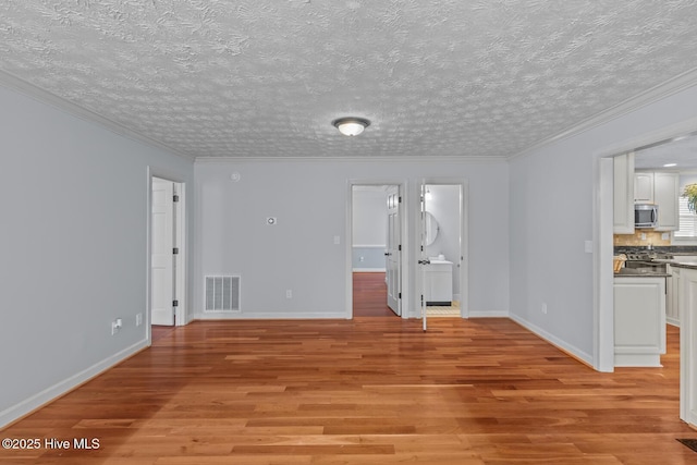 spare room featuring ornamental molding, light wood-type flooring, and a textured ceiling