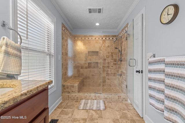 bathroom with a textured ceiling, a shower with door, crown molding, and vanity