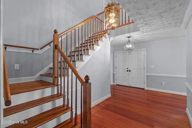 foyer featuring hardwood / wood-style floors, a chandelier, a textured ceiling, and ornamental molding