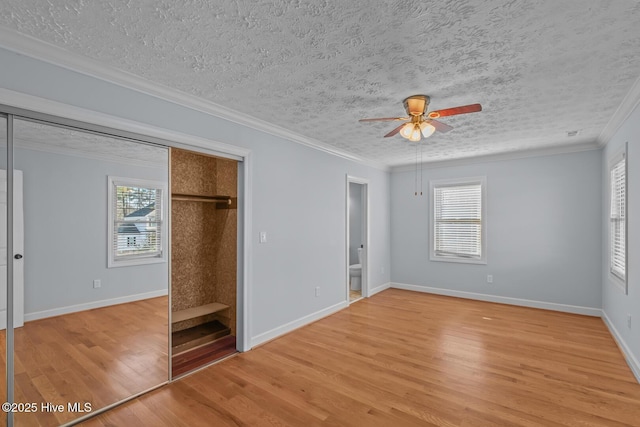 unfurnished bedroom with ensuite bathroom, light hardwood / wood-style flooring, a textured ceiling, and ornamental molding