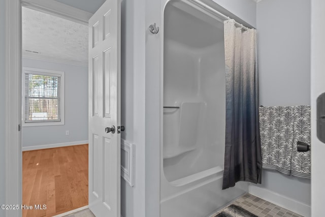 bathroom featuring a textured ceiling, ornamental molding, shower / bath combination with curtain, and hardwood / wood-style floors