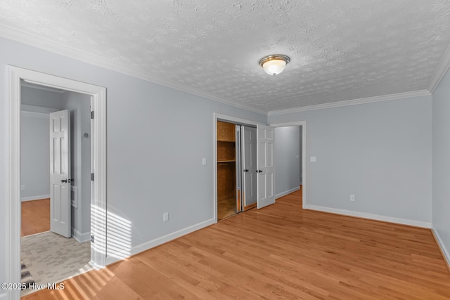 unfurnished room featuring light wood-type flooring, crown molding, and a textured ceiling