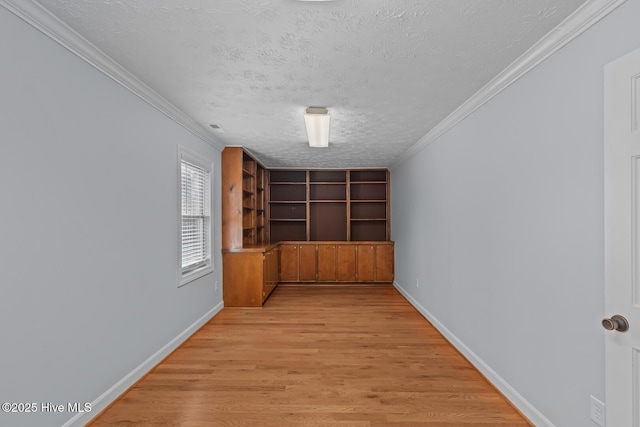 unfurnished room featuring light wood-type flooring, crown molding, and a textured ceiling