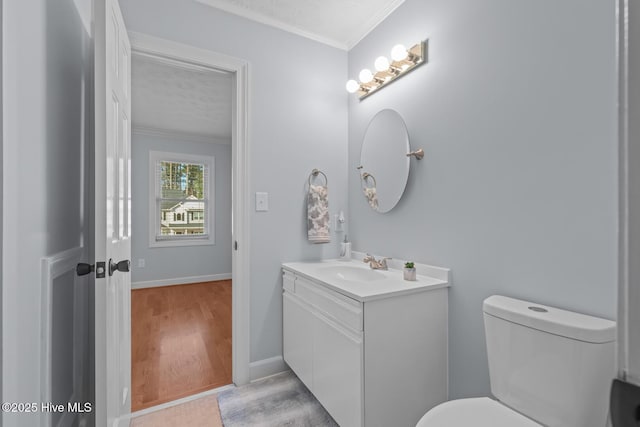 bathroom with ornamental molding, vanity, toilet, and wood-type flooring