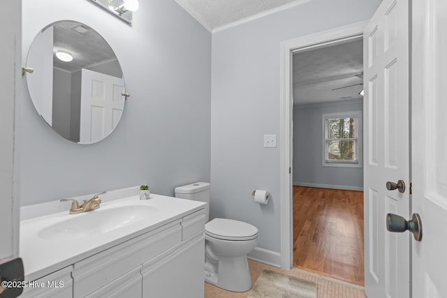 bathroom with toilet, a textured ceiling, vanity, and ornamental molding