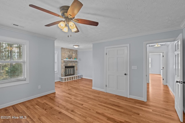 unfurnished living room with light hardwood / wood-style flooring, crown molding, a textured ceiling, and a fireplace