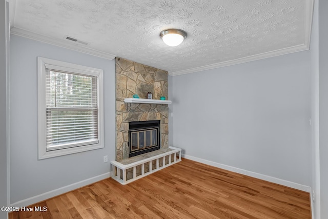 unfurnished living room featuring a fireplace, crown molding, wood-type flooring, and a textured ceiling