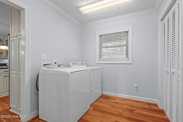 washroom with light wood-type flooring, a textured ceiling, separate washer and dryer, and ornamental molding