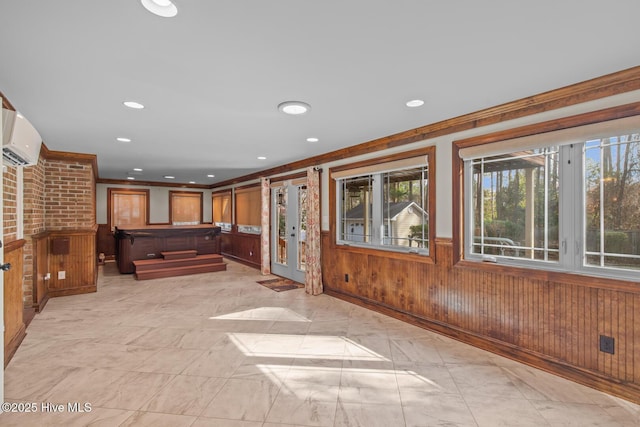 interior space with ornamental molding, wooden walls, and a wall mounted air conditioner