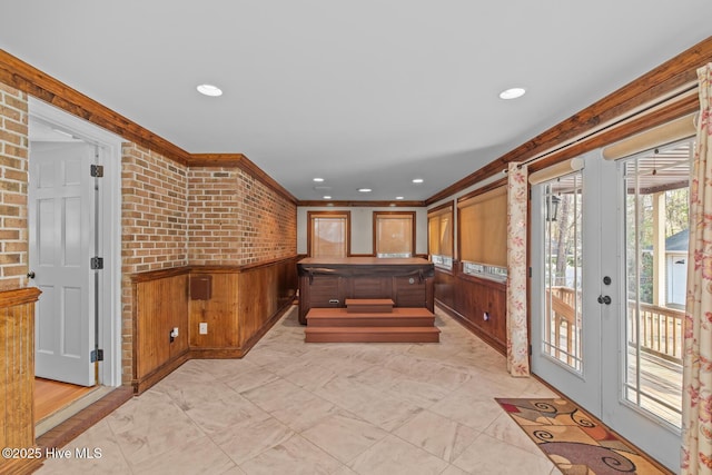 interior space featuring french doors, brick wall, and ornamental molding