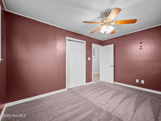 unfurnished bedroom with carpet, a ceiling fan, baseboards, a textured ceiling, and a closet