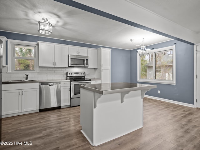 kitchen featuring a kitchen bar, dark countertops, white cabinets, and stainless steel appliances