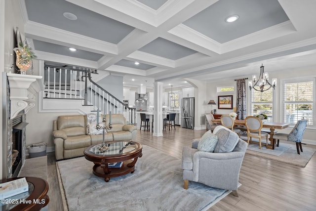 3953 Palm St SE, Bolivia, NC 28422 - living area featuring a fireplace, a chandelier, stairs, beamed ceiling, and light wood-style flooring