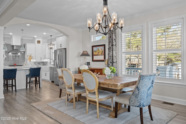 3953 Palm St SE, Bolivia, NC 28422 - dining room with arched walkways, a chandelier, light wood-style floors, ornamental molding, and baseboards