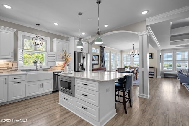 3953 Palm St SE, Bolivia, NC 28422 - kitchen with stainless steel appliances, a chandelier, a sink, ornate columns, and a kitchen island
