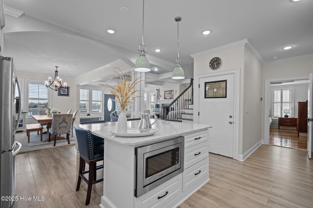 3953 Palm St SE, Bolivia, NC 28422 - kitchen with stainless steel appliances, crown molding, light wood-style floors, a kitchen breakfast bar, and white cabinets