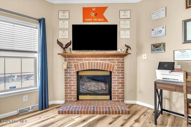 living room featuring visible vents, a fireplace, baseboards, and wood finished floors