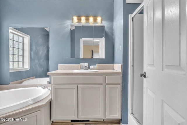 bathroom with a shower with door, a bath, and vanity