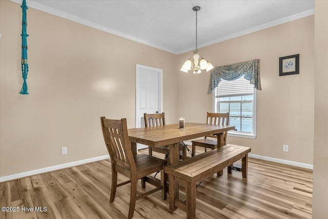 dining space featuring ornamental molding, baseboards, a notable chandelier, and light wood finished floors