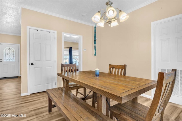 dining space with a textured ceiling, crown molding, baseboards, light wood-type flooring, and an inviting chandelier