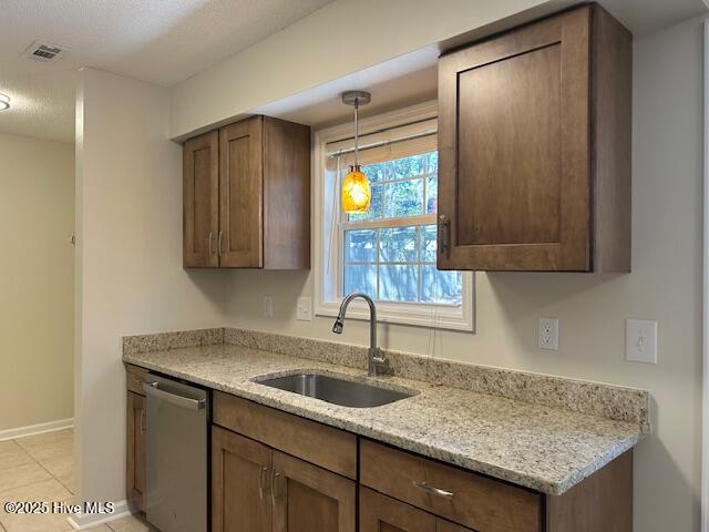 kitchen featuring sink, light tile patterned flooring, stainless steel dishwasher, hanging light fixtures, and light stone countertops