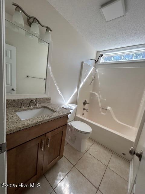 full bathroom featuring washtub / shower combination, tile patterned flooring, toilet, a textured ceiling, and vanity