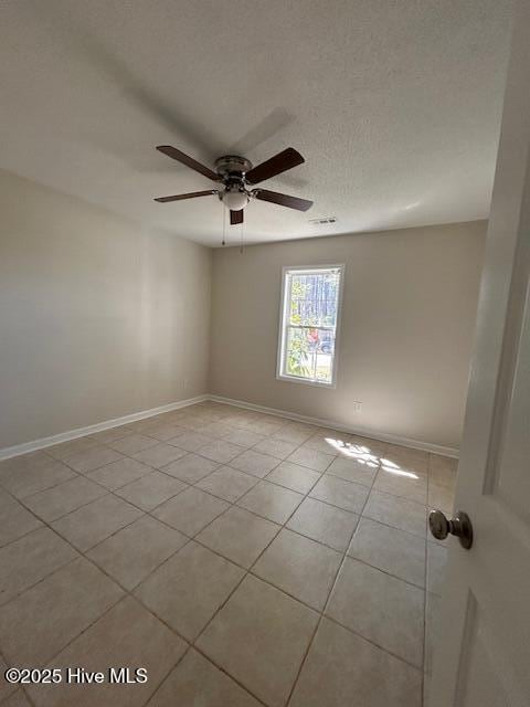 tiled spare room with a textured ceiling and ceiling fan