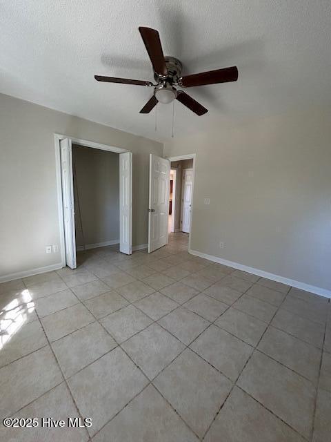 unfurnished bedroom featuring light tile patterned flooring, a closet, ceiling fan, and a textured ceiling