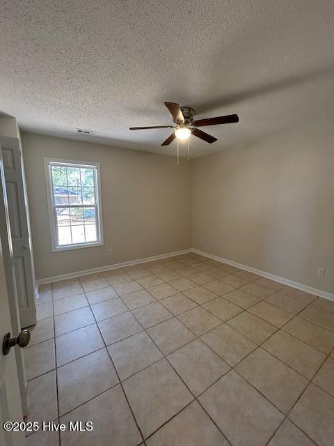 unfurnished room featuring a textured ceiling, light tile patterned flooring, and ceiling fan