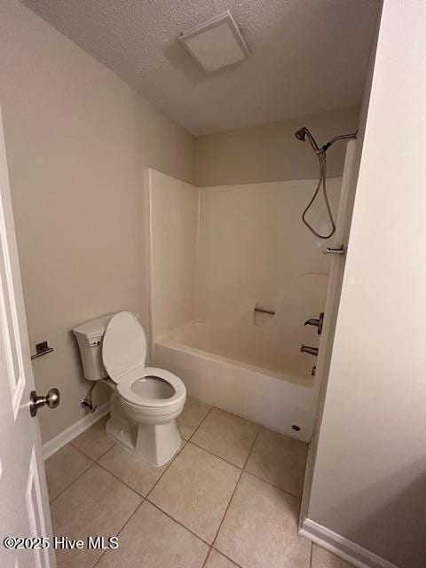 bathroom with a textured ceiling, toilet, tile patterned flooring, and shower / washtub combination