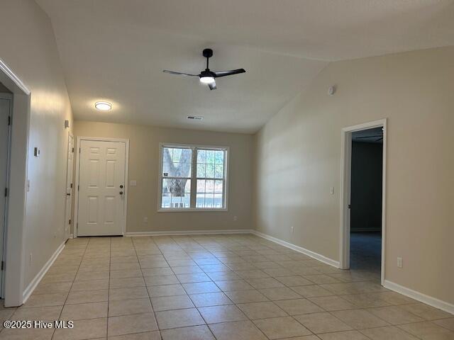 tiled empty room with vaulted ceiling and ceiling fan