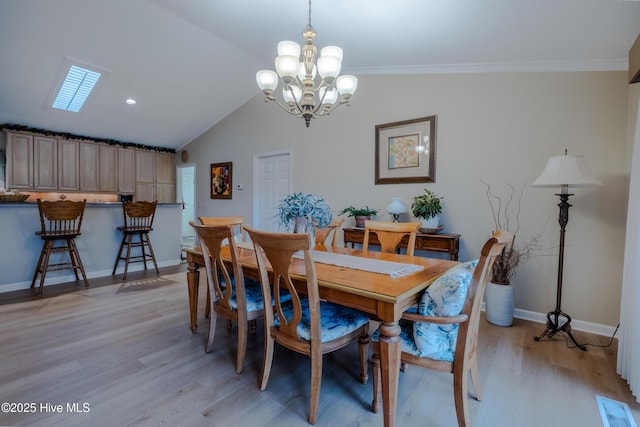 dining room featuring a notable chandelier, lofted ceiling, light wood-style flooring, ornamental molding, and baseboards