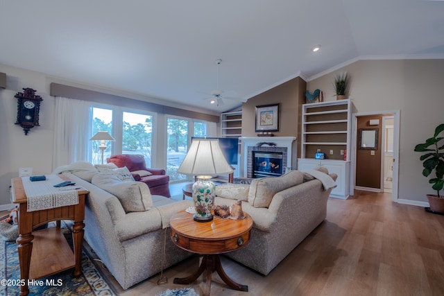 living room featuring lofted ceiling, light wood-style floors, crown molding, baseboards, and a brick fireplace