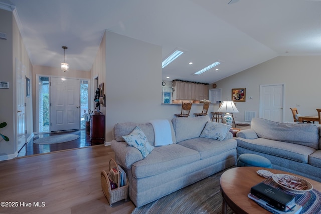 living room featuring visible vents, lofted ceiling, baseboards, and wood finished floors