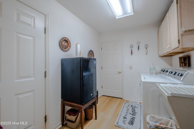 washroom featuring cabinet space, independent washer and dryer, and light wood-type flooring