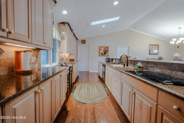 kitchen featuring dishwasher, vaulted ceiling, light wood-style flooring, black electric cooktop, and a sink