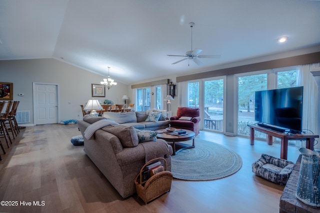 living area with visible vents, ceiling fan with notable chandelier, light wood-style floors, and vaulted ceiling