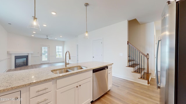 kitchen with pendant lighting, appliances with stainless steel finishes, a sink, and white cabinets