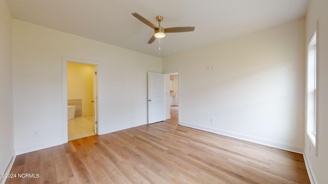 unfurnished bedroom with ensuite bathroom, light wood finished floors, multiple windows, and baseboards