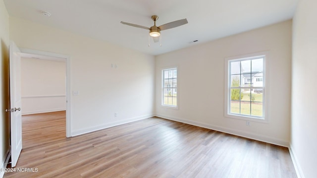 empty room with baseboards, ceiling fan, visible vents, and light wood finished floors