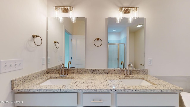 bathroom featuring a stall shower, a sink, and double vanity