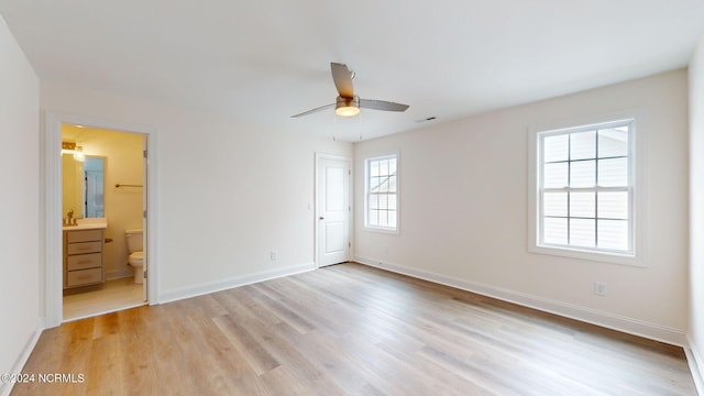 unfurnished bedroom featuring light wood-style floors, multiple windows, and baseboards