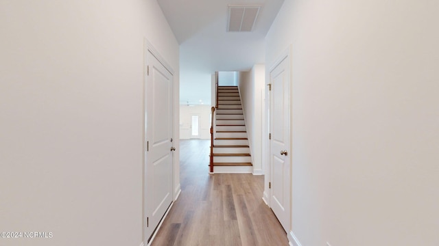 hall featuring light wood-type flooring, visible vents, and stairs