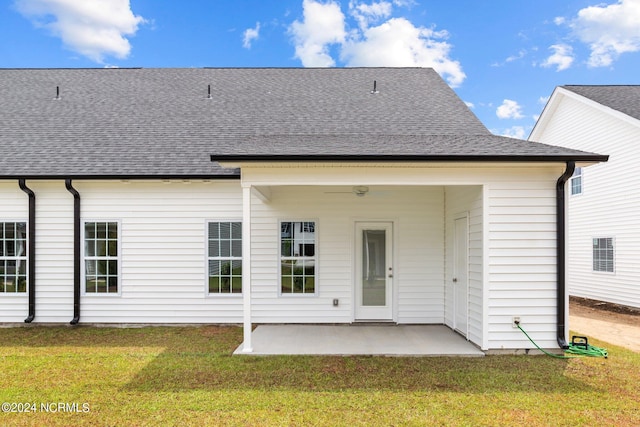 rear view of house with a patio, a lawn, and roof with shingles