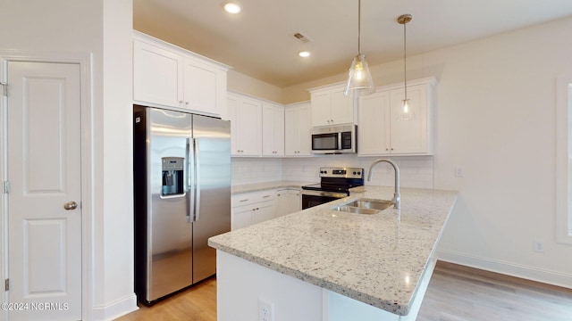 kitchen featuring appliances with stainless steel finishes, white cabinets, a sink, and a peninsula