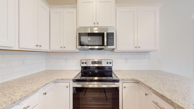 kitchen with stainless steel appliances, white cabinetry, backsplash, and light stone counters