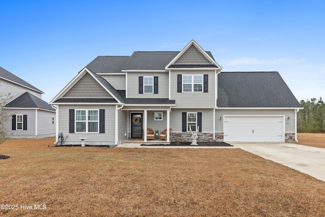 craftsman inspired home with concrete driveway, a front lawn, an attached garage, and a shingled roof