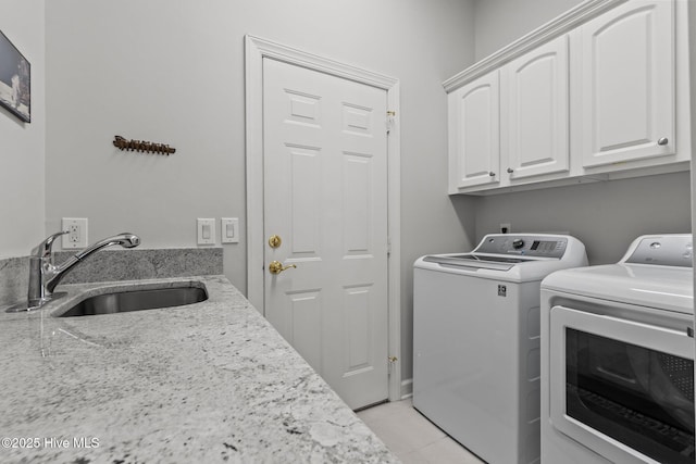 washroom with a sink, cabinet space, light tile patterned floors, and washer and dryer