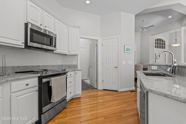 kitchen with light wood-style flooring, ceiling fan, a sink, white cabinets, and appliances with stainless steel finishes