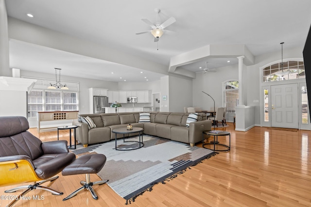 living room featuring recessed lighting, light wood-type flooring, a ceiling fan, and decorative columns